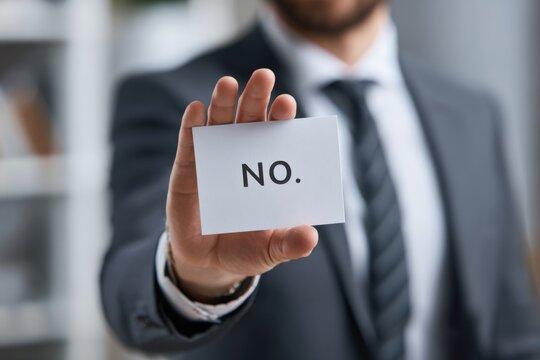 An Individual in Professional Attire Firmly Displays a Card with the Bold Message 'NO.' Highlighting Rejection or Dismissal in a Business Environment
