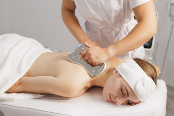 Professional guasha back massage with metal tool in spa clinic