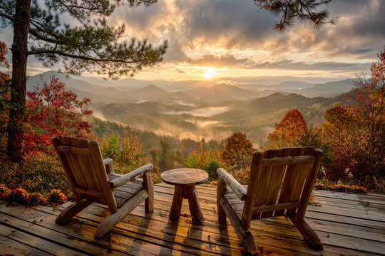 Two wooden chairs on a rustic deck overlooking a vibrant autumn forest and misty mountain sunrise under a dramatic cloudy sky in a peaceful natural setting
