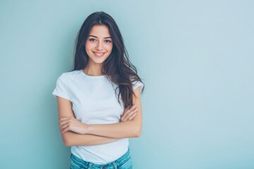 Obraz premium Bright smiling young woman with long dark hair wearing casual white t-shirt standing against pastel blue background.