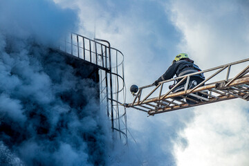 Firefighter on a ladder fighting smoke during a building fire