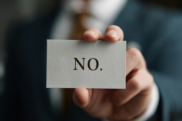 A Formal Businessman Holding a Card Displaying the Word 'NO' in Bold Text, Signifying Refusal or Rejection in Professional Contexts