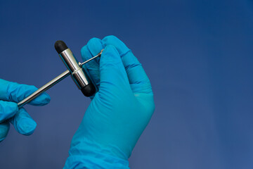 Blue Gloved Hands Holding medical hammer and medical needle On blue Background,