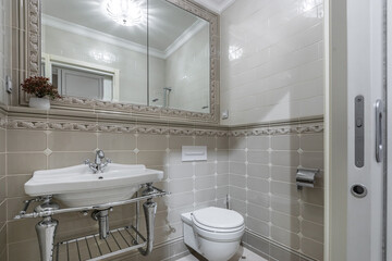 The elegant bathroom is equipped with a vintage-style sink, a modern toilet, an elegant mirror and gorgeous lighting in soft neutral tones.