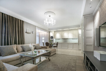 Elegant modern living room with kitchen area showcasing sophisticated furnishings and soft lighting.