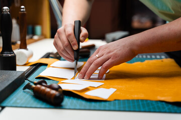 Leather crafting with precision knife and templates. Leather Cutting with Knife and Templates. Artisan cuts premium leather with sharp knife and paper templates.
