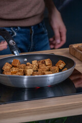 Tofu cubes being sauteed in a stainless steel pan on a stovetop, showcasing a healthy vegetarian dish with vibrant colors and textures, ideal for plant-based cuisine enthusiasts