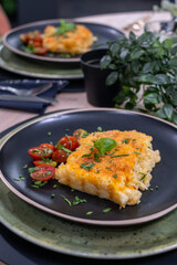 Creamy macaroni and cheese served on a black plate with cherry tomatoes and herbs, showcasing a delicious comfort meal with vibrant colors and inviting presentation