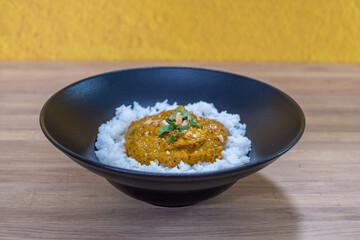 Chicken curry served on a bed of fluffy white rice in a black bowl, garnished with fresh herbs, showcasing a vibrant and appetizing meal concept
