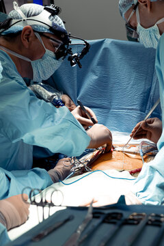 Doctor and assistant team in blue uniform do surgery inside operating room in modern hospital. Surgeons do mini invasive heart operation. Medical device used in hospital. High quality photo
