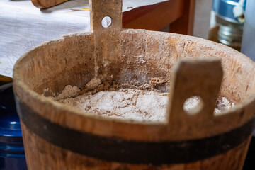 Wooden container filled with flour sits on a kitchen table, surrounded by baking tools and ingredients, showcasing the art of homemade bread preparation with copy space