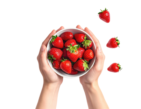 Hands holding a white bowl filled with fresh strawberries.  Strawberries are also scattered in the air