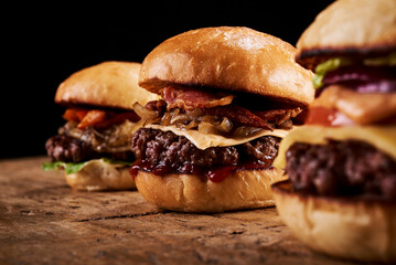 Three hamburgers on a wooden table
