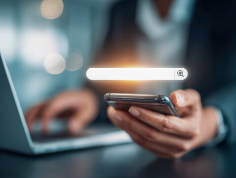 Businessman using smartphone with laptop in background and illuminated digital search bar icon representing online information and data retrieval concepts