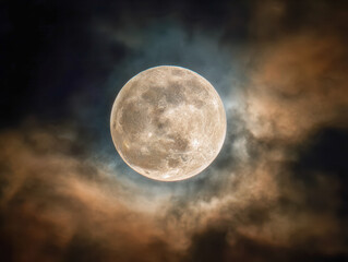Stunning full moon glowing brightly while surrounded by swirling dramatic clouds in a dark night sky creating a mystical and captivating atmosphere