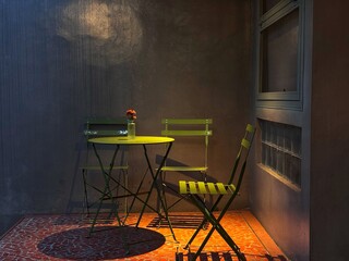 A cozy, dimly lit balcony with a small yellow bistro table and matching chairs, creating an intimate and peaceful atmosphere. A single flower in a vase adds a touch of color to the scene