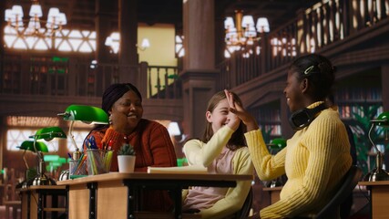 African american teacher providing instruction to diverse girls during private sessions, assisting with homework and school projects in a library. Doing tutoring activity for success. Camera B.
