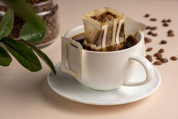 Drip bag of fresh drink in a glass with coffee beans. Drip coffee using a paper type filter.