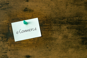 There is a piece of paper with the word e-Commerce. It is an abbreviation for E-Commerce as eye-catching image.