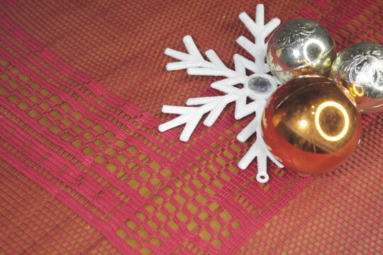Estrella blanca y bolas de navidad colocadas sobre un mantel color rojo.