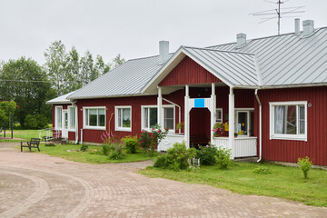 Obraz premium Charming Red Cottage Surrounded by Lush Greenery, Featuring a Welcoming and Inviting Entrance