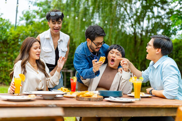 Group of Happy Asian people diverse friends enjoy and fun celebration meeting social gathering dinner party eating food, drinking cocktail and talking together in the garden at restaurant in evening.
