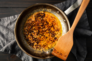 Freshly Made Chili Crisp Oil in a Skillet: Red Chili flakes and fresh garlic cooked in a stainless steel frying pan with melted butter