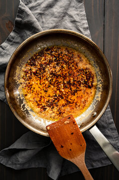 Freshly Made Chili Crisp Oil in a Skillet: Red Chili flakes and fresh garlic cooked in a stainless steel frying pan with melted butter