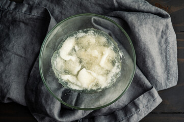 Bloomed Gelatine in a Glass Bowl: Directly above a bowl of plain gelatin after blooming with cold water