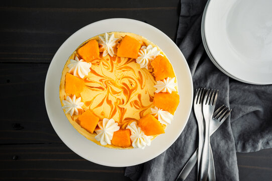 Mango Mousse Cake Overhead View: Directly above a mousse cake with mango swirl, cream cheese frosting, and fresh mango decorations