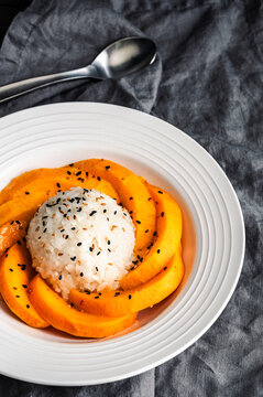 Mango Sticky Rice Drizzled with Coconut Sauce in a Shallow Bowl Close-up: Thai dessert with glutinous rice, fresh fruit, and toasted sesame seeds