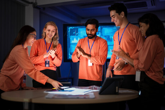 A successful team of app developers proudly presents their completed project. The diverse group is happy with the results of their hard work and effective collaboration.