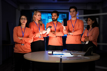 A diverse application development team presents their new mobile app on smartphones with blank mockup screens, ready for branding. This is a presentation of a new UI/UX design or product launch.