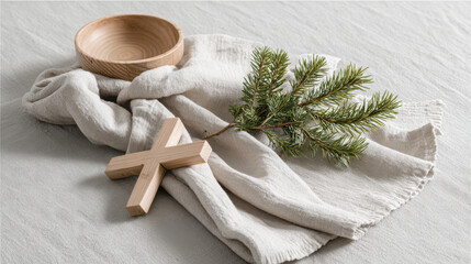 minimalist still life featuring wooden cross placed gently on linen tablecloth beside pine branch