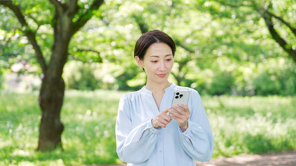 屋外でスマートフォンを使う40代女性