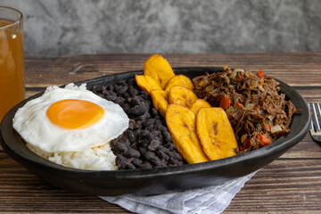 Delicious Venezuelan pabellón criollo with rice, beans, shredded beef, plantain and fried egg. Authentic Latin food photography