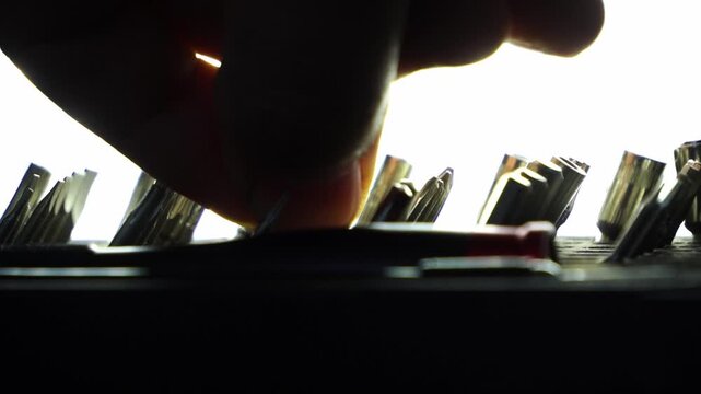 On a dark background, a hand picks a screwdriver bit from an organized box set&mdash;precision tools for DIY repair, maintenance, and professional hardware work.