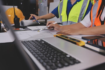 Closeup of team of industrial engineers meeting analyze machinery blueprints consult project on...