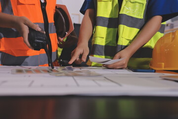 Closeup of team of industrial engineers meeting analyze machinery blueprints consult project on table in manufacturing factory. Working in manufacturing plant or production plant.