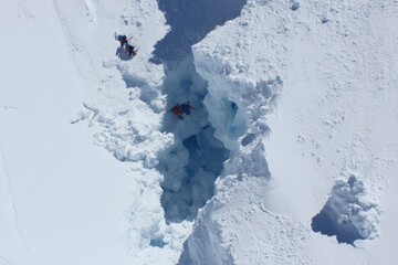 High-angle view of a snow-filled crevasse with two figures within