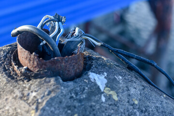 Damaged wires. Aluminum bare wires of electric cable or duct tape torn beside concrete poles. Selective focus	

