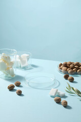 Lab glassware decorated with shea butter cream, shea nuts and leaf on pastel blue background. Perfect reference for skincare product design and branding.