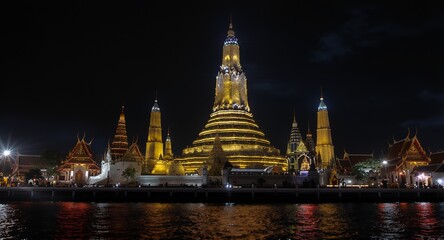 Naklejka premium Nighttime View of Illuminated Asian Temple Complex on Riverbank