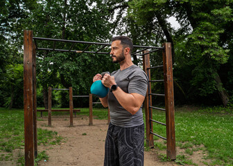 Obraz premium Focused handsome 40 years old muscular man exercising outdoors with kettle bell , outdoors workout 
