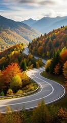 A winding mountain road meanders through a vibrant autumn landscape, showcasing a scenic route amidst colorful foliage and towering peaks.