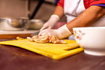 Woman preparing raw chicken for cooking in kitchen