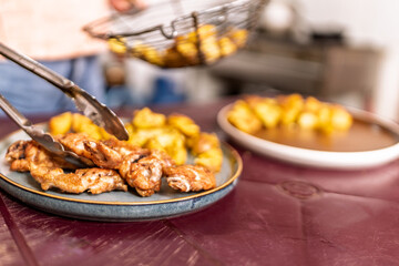 Preparing fried chicken wings and potatoes