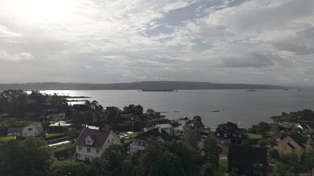 Aircraft Carrier USS Gerald R. Ford Sailing In Oslo Fjord Seen From The Seaside Town In Oslo, Norway. - aerial shot