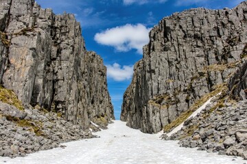 Rocky mountain pass, snow-filled gorge, dramatic cliffs