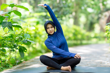 Healthy Asian woman in sportswear do yoga at the park. Moslem woman with sportwear.
